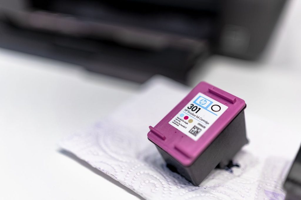 pexels-photo-7639358 A close-up of a printer ink cartridge resting on a paper towel, showcasing its design and details.